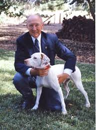 A man kneeling down next to a dog.